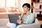 Thoughtful middle aged European woman with laptop in living room