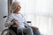 Thoughtful middle aged old hoary woman sitting in wheelchair.