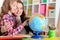 Thoughtful mother and daughter sitting at table with globe