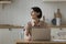 Thoughtful positive mature freelance employee woman working at kitchen table