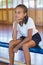 Thoughtful schoolgirl sitting in basketball court