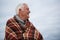 Thoughtful senior man wrapped in shawl at the beach