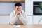 Thoughtful serious young asian man looking away. student writer sit at home office desk with laptop thinking of inspiration search