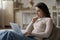 Thoughtful serious young laptop user woman relaxing on couch