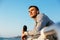 Thoughtful sportsman standing on quay, with bottle of water