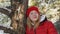 Thoughtful teenage girl leaning at tree in winter forest