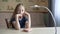 Thoughtful teenage girl sitting at desk and thinking with pen in hands