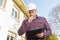 Thoughtful worker builder in hardhat on background construction