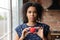 Thoughtful young african ethnicity female volunteer holding heart in hands.