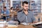 Thoughtful young man engaged in research, working with laptop and books