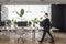 Thoughtful young man walking in modern coworking office interior with equipment, furniture, decorative plants and matte glass