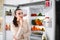 Thoughtful young woman near open refrigerator