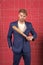 Threatening violence. Aggressive business strategy. Businessman formal elegant suit pink background. Man hold wooden bat