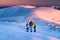 Three active hikers watching the sunrise scenery in winter landscape. Hiking together, teamwork in mountains, concept photo.