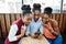 Three african american girls sitting on the table of caffe and looking on mobile phone