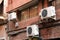 Three air conditioning units on the outside red brick wall of a