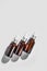 three amber dropper glass bottles with liquid serum or with remedy on grey background. Mockup