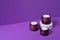 Three amber glass jars with trendy geometric shape on a violet background.