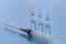 Three ampullas and expendable syringe isolated on blue background. Medical health or drugs addiction concept.