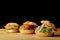 Three appetizing burgers on wooden table