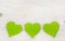 Three apple green hearts on white shabby style wooden background