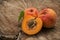 Three apricots, one is divided into half on a wooden background