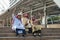 Three Arabian businessman sitting on stairs and raise their hands in modern city. Concept Success