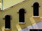 Three arched windows in yellow stucco exterior wall stepping up along an interior stair