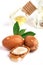 Three argan nuts with green leaves glass bottles on isolated white background. Chopped argan nut with a drop of oil