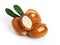 Three argan nuts with green leaves on an isolated white background. Chopped argan nut with a drop of oil. Whole and