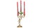 Three-armed candlestick with red candles, held by a figurine, made of brass in old decorative style, isolated on a white backgroun