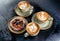 Three aroma cappuccino coffee cups with pictures and bun with berries