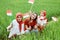 Three Asian girls smile posing hold a small flag sitting in the middle of rice fields