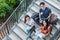 Three Asian young campus students enjoy tutoring and reading books together at library stair. Friendship and Education concept.