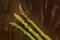 Three asparagus over dark brown wooden