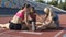 Three athlete girls sitting on sports field and stretching, workout and fitness