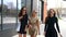 Three attractive young girl holding shopping bags while pass near the store.Girls laughing and smiling at the camera