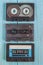 Three audio cassettes in black cases lie on a blue wooden background