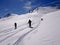 Three backcountry skiers enjyoing a ski descent in fresh powder in the Swiss Alps