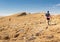 Three backpackers walking ascending mountain rock desert slope.