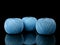 Three balls of blue string on a black background with reflection