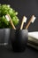 Three bamboo toothbrushes in a black glass with plant on a dark background