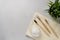 Three bamboo toothbrushes, tooth powder and towel on a light gray concrete background.