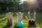 Three barefoot children lie on the grass with their legs up and arms up