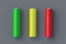 Three batteries red yellow green color aa or aaa size on gray background