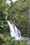 Three Bears Falls, also known as Upper Waikani Falls, cascading down a cliffside in a rain forest in Haiku, Maui