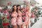 Three beautiful bridesmaid women in a pretty dress with flowers posing over pink blooming flowers background. Fashion photo.