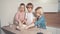 Three beautiful children help in the kitchen and mix the dough in a white plate.