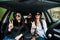Three beautiful female friends make peace signs while seated car