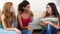 Three beautiful friends chatting while sitting on couch